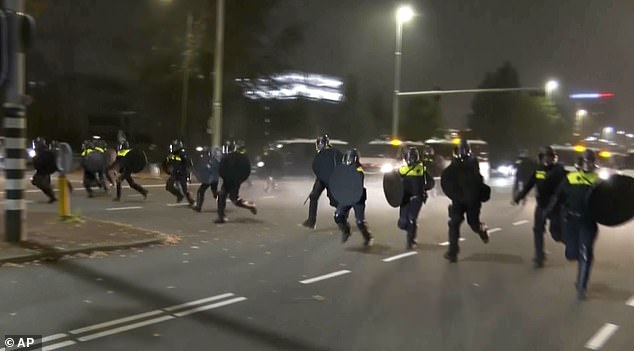 Police in riot gear run towards protesters after pro-Palestinian supporters marched near the Johan Cruyff Arena in Amsterdam