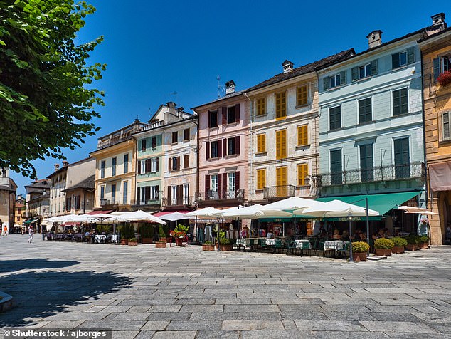 In the town of Orta San Giulio, Kate explores Piazza Motta (seen here), with its 'faded pastel-hued houses of ochre, yellow and pink'