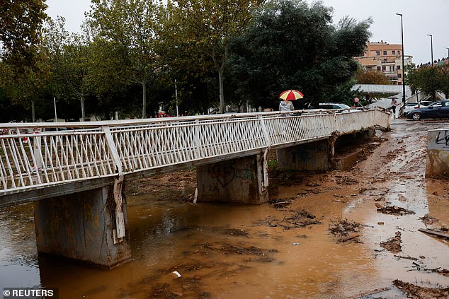 A person crosses the La Saleta ravine that recently overflowed due to heavy rainfall in Aldaia, Valencia, Spain, November 13, 2024