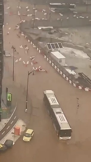 A bus is seen abandoned as cars plough through deep floodwaters in Malaga