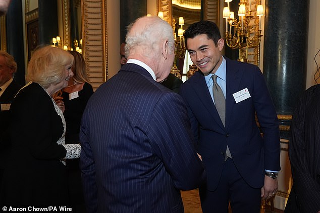 Charles pictured meeting Henry Golding - during a reception to mark the centenary of the Film and TV charity