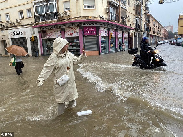 A woman takes a photo of a flooded street in Malaga, Andalusia, Spain, 13 November 2024