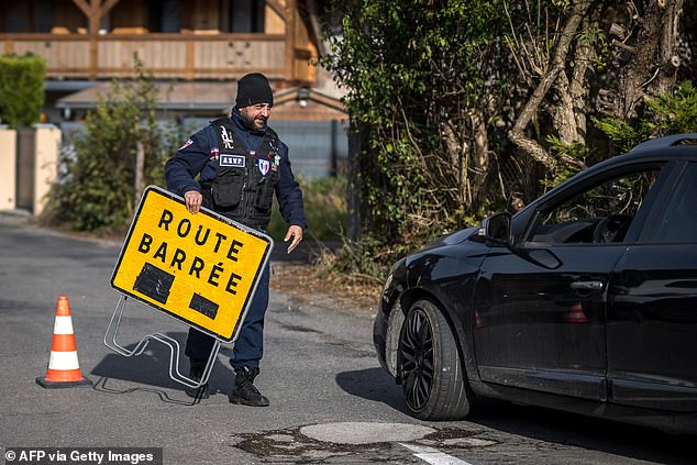 A surveillance officer closes the road to the hamlet above Taninges, French Alps, where three children were found dead the day before, on November 13, 2024