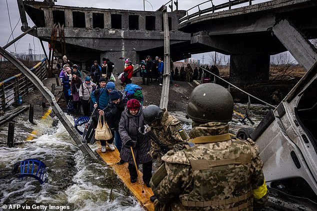 Evacuees cross a destroyed bridge as they flee the city of Irpin, northwest of Kyiv, on March 7, 2022