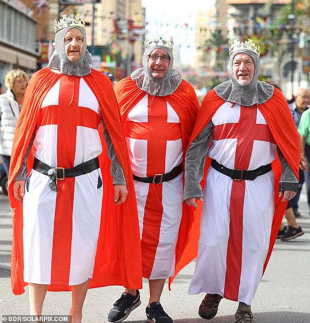 Three men dress as English knights with crowns on their heads during the parade