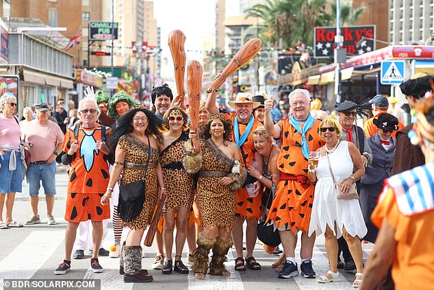 Pictured: A group of attendees dressed as cavemen and women holding inflatable clubs