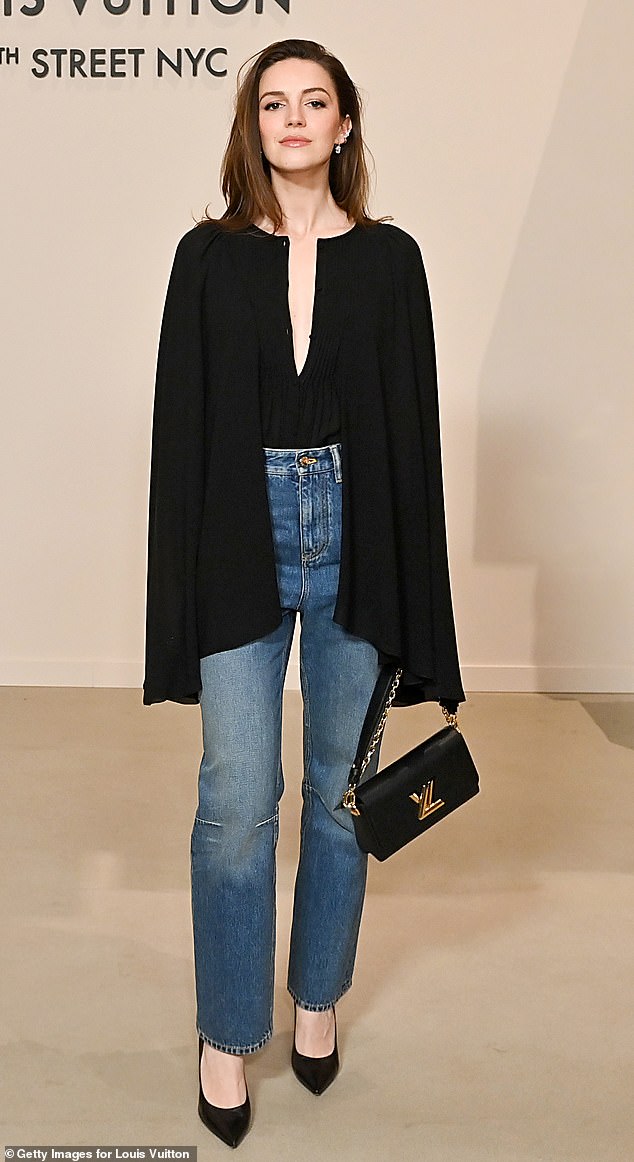 Ella Hunt was chic wearing a black top with a deep, plunging neckline that was tucked into the waist of classic, denim jeans