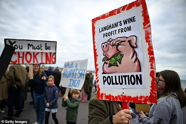 Protestors hold up signs saying 'you must be choking' and 'Langham Wine profit from pollution' - Langham wine has the same owners as Portland Port