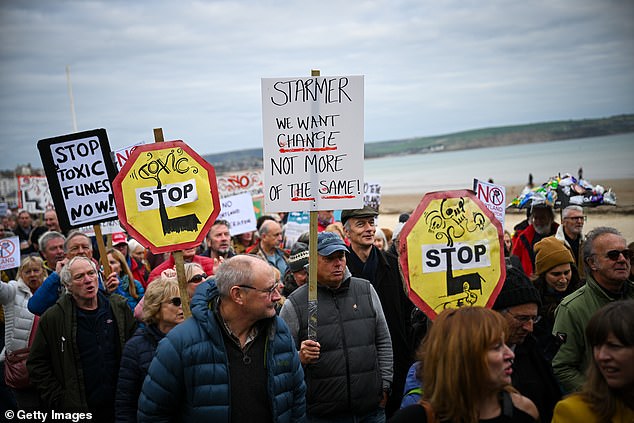 Crowds march with placards, one which says 'stop toxic fumes now', another says 'Starmer We want change not more of the same'