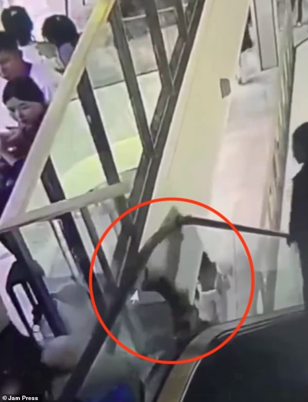 She loses balance as the escalator begins to drag her down. The woman then  desperately tries to grip the handrail as she suddenly falls through a small gap between the stairs and the guard rail