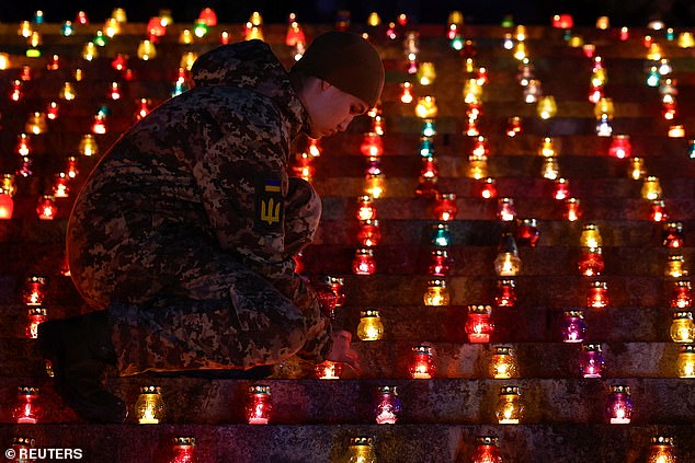 A military cadet lights a candle during a commemorative ceremony on the 1000th day of Russia's full scale attack on Ukraine