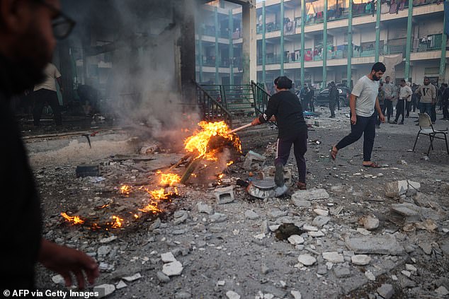 A displaced Palestinian youth tries to control a fire amid the debris following an Israeli strike that hit a UN-run school where people had taken refuge, in the Nusseirat refugee camp in the central Gaza Strip on November 20, 2024