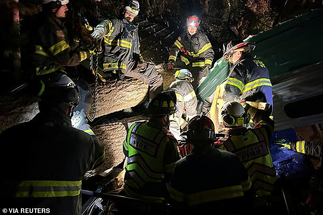 Firefighters and paramedics respond after a tree fell onto a trailer in Maple Valley, Washington on Tuesday, trapping two people inside