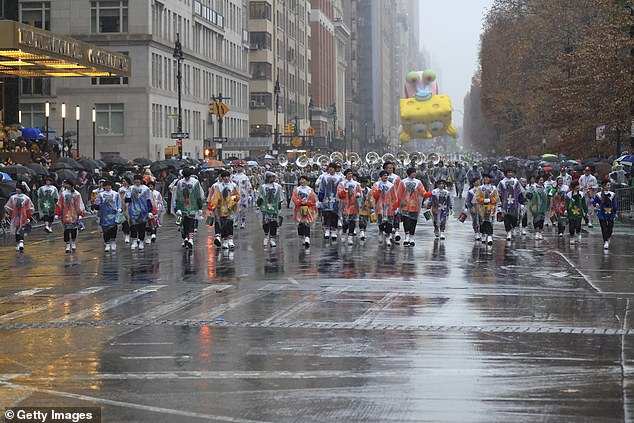 Parade workers trudge through the rain carrying the Spongebob float