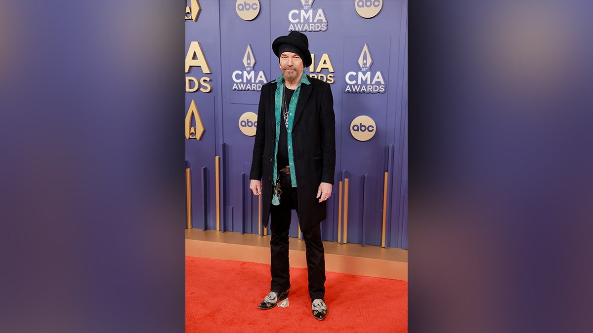 Billy Bob Thornton walked the red carpet at the 2024 CMA Awards in a black jacket, blue shirt and black hat.