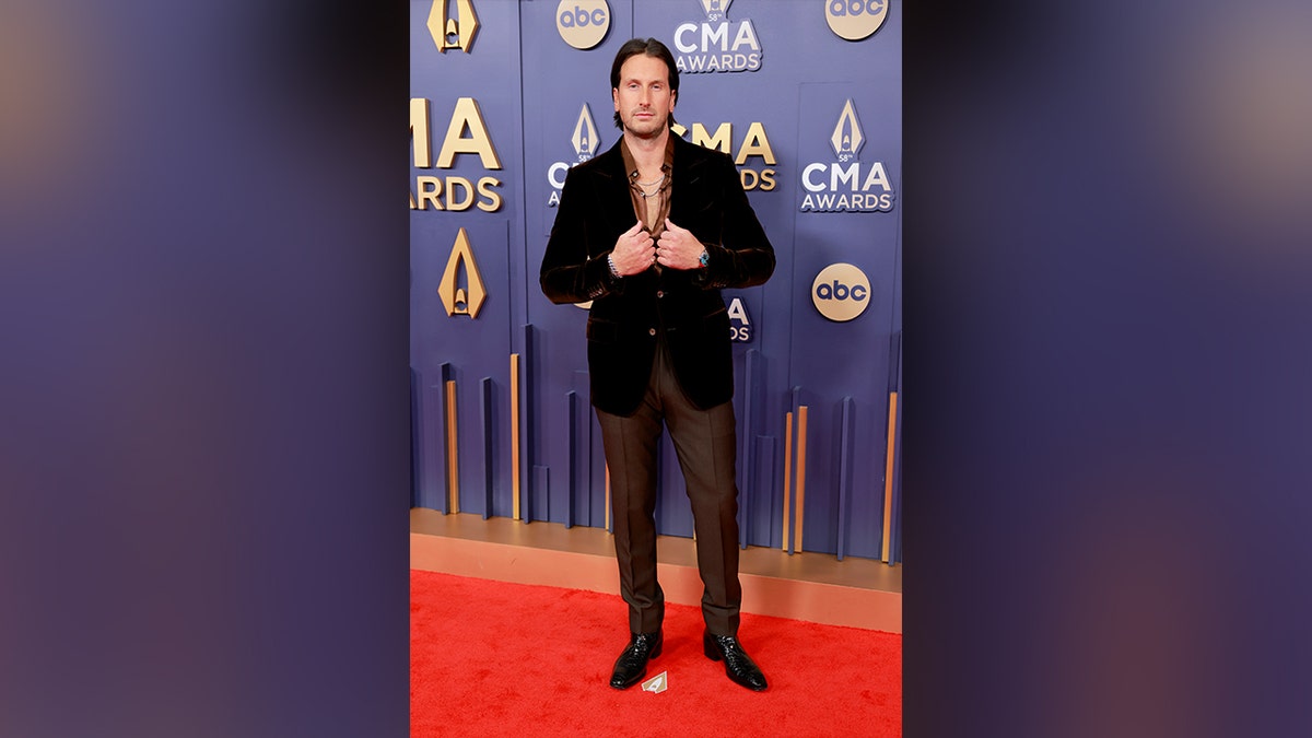 Russell Dickerson at the 2024 CMA Awards in a black jacket and brown slacks.