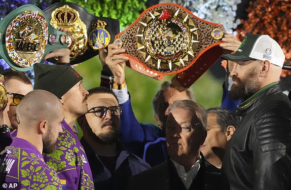 Boxers Britain's Tyson Fury, right, and world champion Ukraine's Oleksandr Usyk, center left, face off on stage during the weigh-in for their WBA, WBO, and WBC heavyweight title bout in Riyadh, Saudi Arabia, Friday, Dec. 20, 2024. (AP Photo/Frank Augstein)