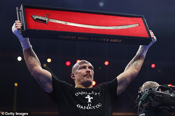 RIYADH, SAUDI ARABIA - DECEMBER 21: Oleksandr Usyk holds up a 'Ukraine Wow: Mazepa's Saber' following victory in the IBF, IBO, WBA, WBC and WBO Undisputed World Heavyweight titles' fight between Oleksandr Usyk and Tyson Fury as part of Oleksandr Usyk v Tyson Fury 2, Reignited card at Kingdom Arena on December 21, 2024 in Riyadh, Saudi Arabia. (Photo by Richard Pelham/Getty Images)