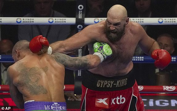 Boxers Britain's Tyson Fury, right, and Ukraine's Oleksandr Usyk compete during their WBA, WBO, and WBC world heavyweight title fight in Riyadh, Saudi Arabia, Saturday, Dec. 21, 2024. (AP Photo/Frank Augstein)