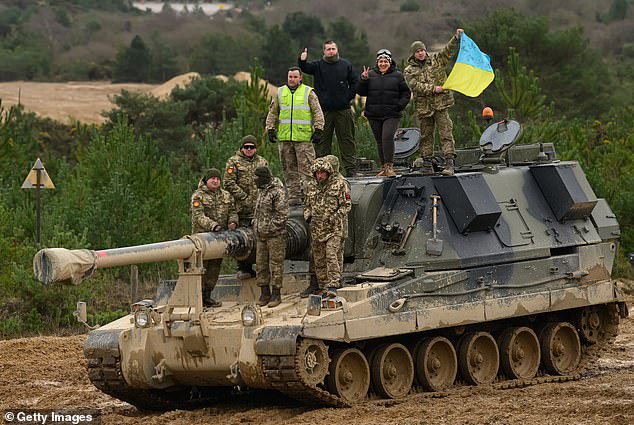 Ukrainian recruits and their British Armed Forces trainers pose for a photograph on an AS90 self-propelled artillery system at a military facility, on February 23, 2023 in Southern England