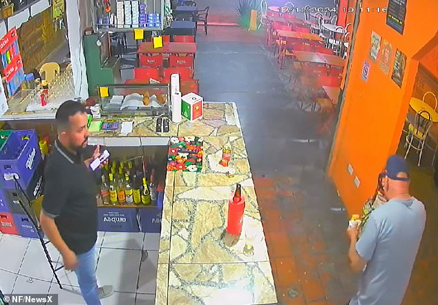 The shop's owner Christian de Souza Amaral - who witnesses the erupting snack - stands open-mouthed in shock as the dazed customer tries to wipe the burning filling from his face