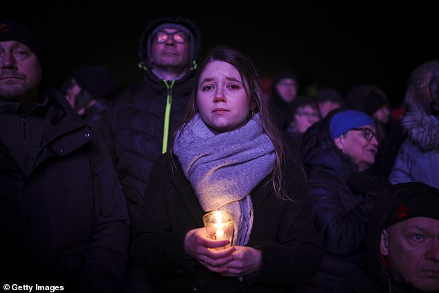 A woman holds a candle as others watch a prayer ceremony outside the Magdeburg Dom church, the day after the devastating attack