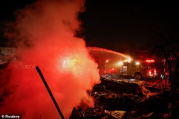 Firefighters hose down a hotspot at a commercial building that burned during the Eaton Fire, in Altadena, California, U.S., January 10, 2025. REUTERS/Fred Greavesâ¿¨