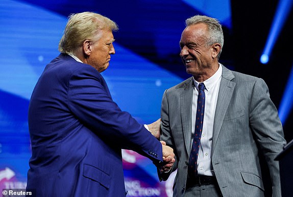 FILE PHOTO: Robert F. Kennedy Jr. and Republican presidential nominee and former U.S. President Donald Trump greet each other at a campaign event sponsored by conservative group Turning Point USA, in Duluth, Georgia, U.S., October 23, 2024. REUTERS/Carlos Barria//File Photo