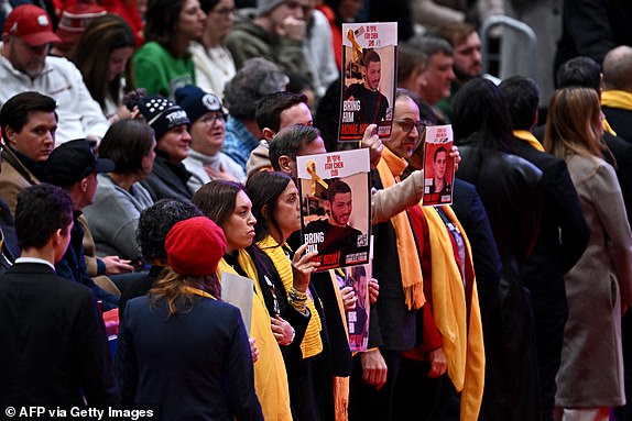 Relatives of Israeli hostages of Hamas hold their photos as Steve Witkoff, special envoy to the Middle East, speaks during the inaugural parade inside Capital One Arena, in Washington, DC, on January 20, 2025. (Photo by ANGELA WEISS / AFP) (Photo by ANGELA WEISS/AFP via Getty Images)