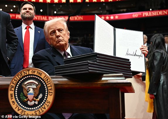 US President Donald Trump holds an executive order he just signed during the inaugural parade inside Capital One Arena, in Washington, DC, on January 20, 2025. (Photo by Jim WATSON / AFP) (Photo by JIM WATSON/AFP via Getty Images)