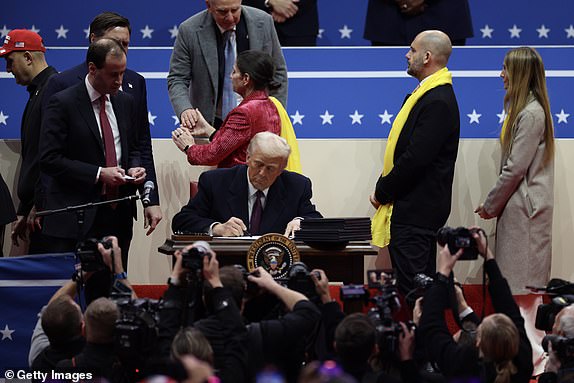 WASHINGTON, DC - JANUARY 20: U.S. President Donald Trump signs executive orders during an indoor inauguration parade at Capital One Arena on January 20, 2025 in Washington, DC. Donald Trump takes office for his second term as the 47th president of the United States. (Photo by Tasos Katopodis/Getty Images)