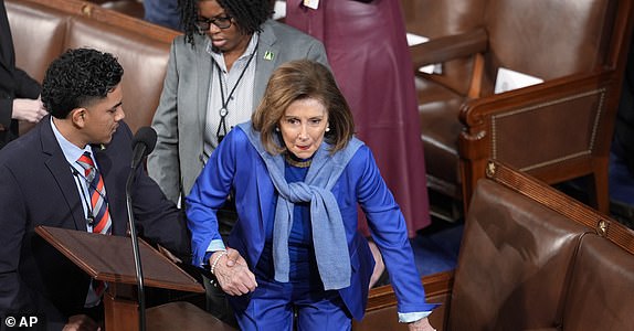 Former Speaker of the House Nancy Pelosi, D-Calif., is helped to her seat as the House of Representatives convenes the 119th Congress with a slim Republican majority, at the Capitol in Washington, Friday, Jan. 3, 2025. It was Pelosi's first time in the chamber since fracturing her hip in a fall in Luxembourg in December, and having emergency surgery. (AP Photo/J. Scott Applewhite)