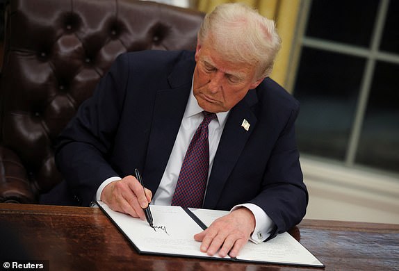 U.S. President Donald Trump signs documents as he issues executive orders and pardons for January 6 defendants in the Oval Office at the White House on Inauguration Day in Washington, U.S., January 20, 2025.  REUTERS/Carlos Barria