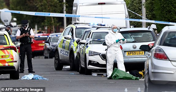 (FILES) Police officers and forensic personnel stand behind a cordon on Hart Street in Southport, northwest England, on July 29, 2024, following a knife attack. Eighteen-year-old Axel Rudakubana, accused of killing three young girls in a stabbing spree last year that sparked the UK's most violent riots in a decade, on January 20, 2025, pleaded guilty to murder. Rudakubana admitted to the killings of three girls -- nine-year-old Alice da Silva Aguiar, six-year old Bebe King, and seven-year-old Elsie Dot Stancombe -- which took place at a Taylor Swift-themed dance class last year in Southport, northwest England, as his trial was due to begin. (Photo by Darren Staples / AFP) (Photo by DARREN STAPLES/AFP via Getty Images)