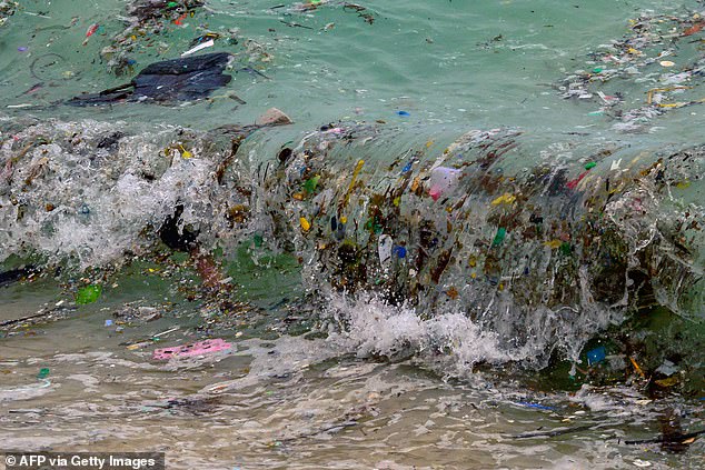 A wave carrying plastic waste and other rubbish washes up on a beach in Koh Samui