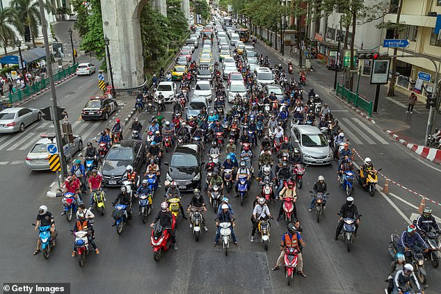 Several scooters and cars waiting at traffic lights on the Ratchadamri Road in Bangkok, Thailand