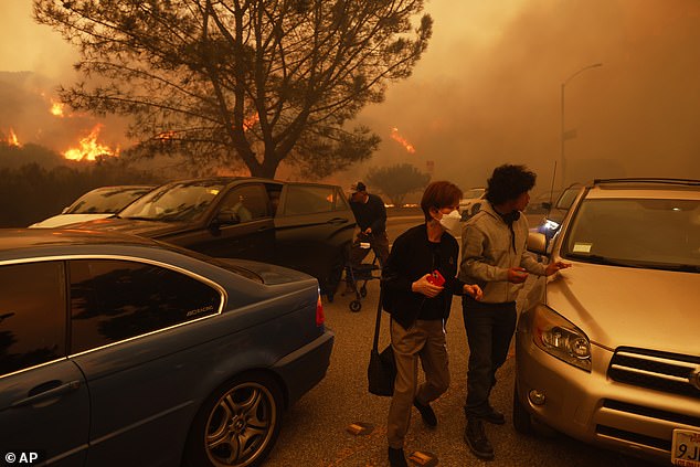 People flee from the advancing Palisades Fire by car and on foot in Los Angeles yesterday