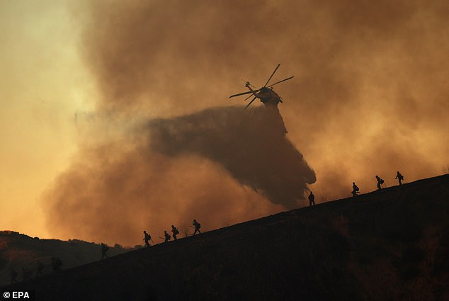 A helicopter drops water on the Kenneth wildfire in the Woodland Hills