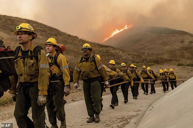 Fire crews walk as they battle the Kenneth Fire in the West Hills section of Los Angeles