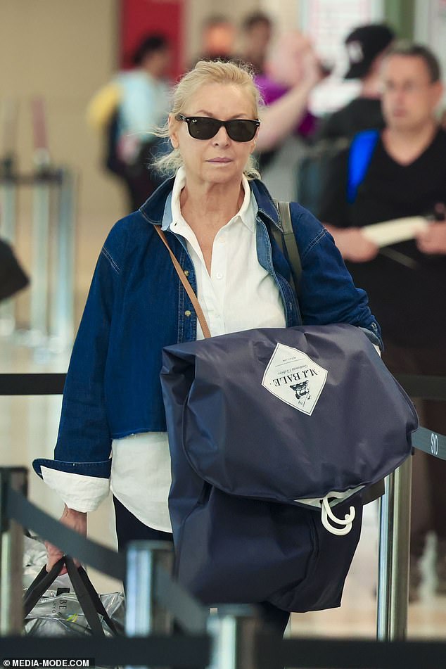 With a cross-body handbag strapped across her torso, Liz didn't have a single hand free as she carried a silver carry-on duffel and an M.J. Bale garment bag