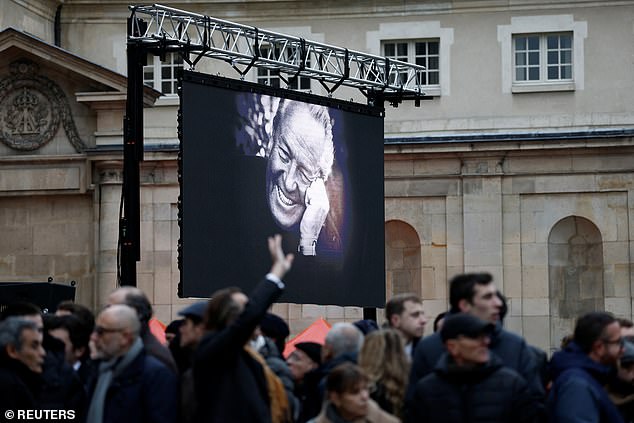 People wait in front of a bigscreen with a photo of late French far-right figure Jean-Marie Le Pen