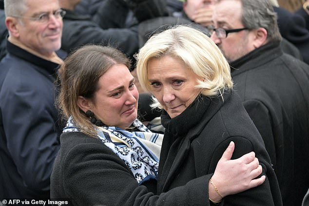 Marine Le Pen was comforted my a fellow mourner outside the service in Paris today