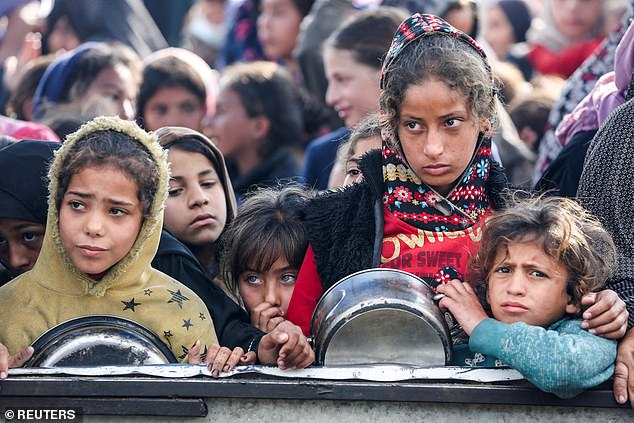 Palestinians gather to receive food cooked by a charity kitchen, before a ceasefire between Hamas and Israel takes effect, in Khan Younis, in the southern Gaza Strip, January 17, 2025