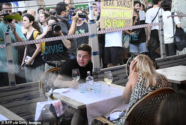 Demonstrators put symbolic cordon on a bar-restaurant window during a protest against mass tourism on Barcelona's Las Ramblas alley, on July 6, 2024