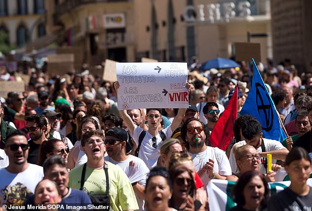 A protester is seen holding up a placard expressing his opinion as he takes part in a demonstration against mass tourism in the city, following protests in the Canary and Balearic islands or Majorca