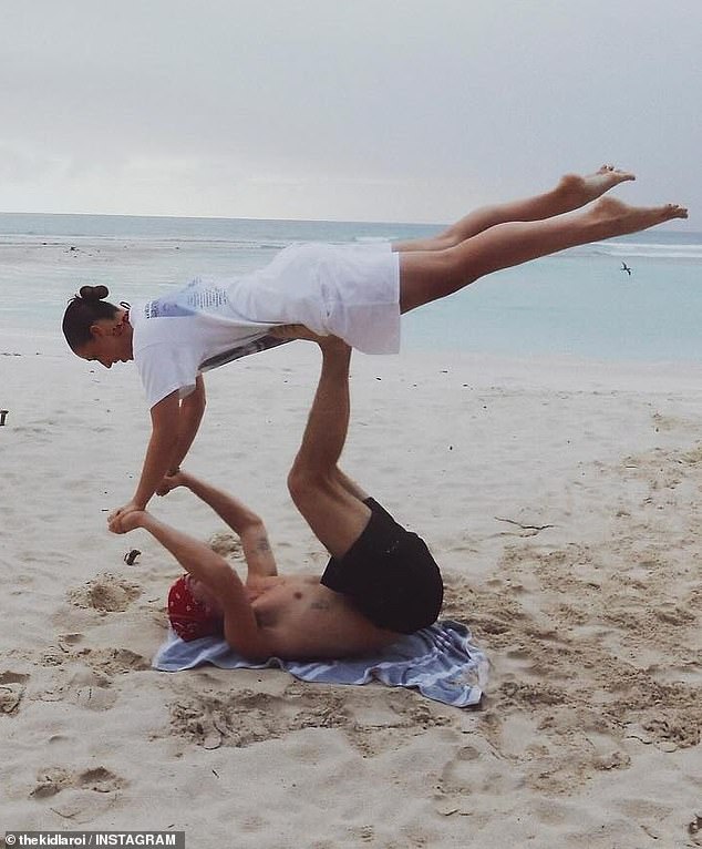 The happy couple hit a gravity-defying two-person yoga pose in the sand