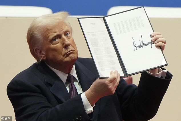 President Donald Trump holds up an executive order after signing it at an indoor Presidential Inauguration parade event in Washington, Monday, Jan. 20, 2025