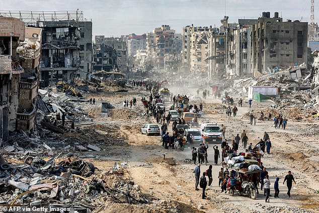 People walk past the rubble of collapsed buildings along Saftawi street in Jabalia in the northern Gaza Strip on January 20, 2025