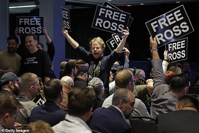 Members of the Libertarian Party stand in chairs while chanting and demanding the release of Ross Ulbricht