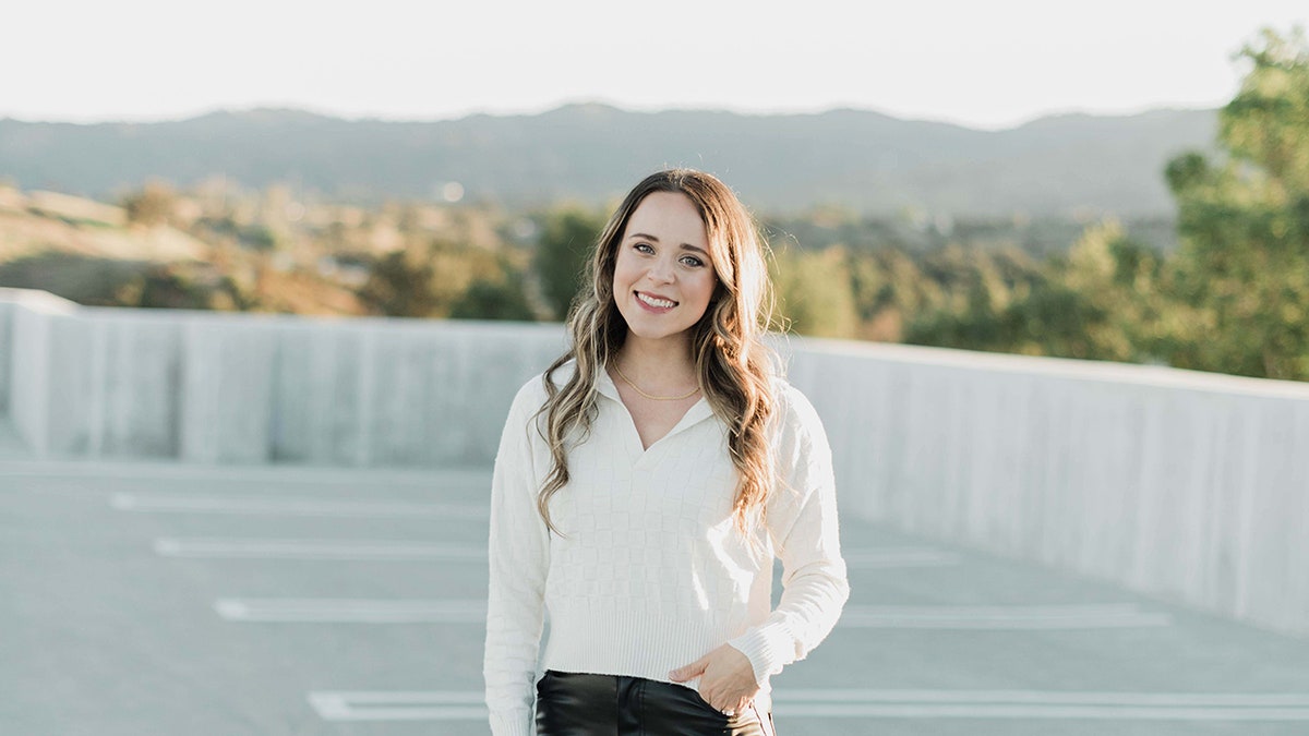 Jinger Duggar Vuolo wearing a white blouse and smiling.